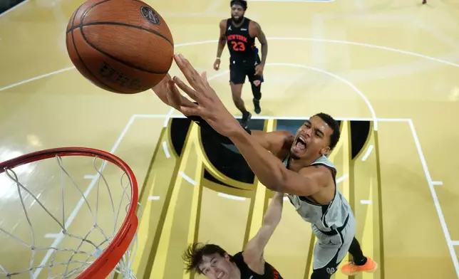 San Antonio Spurs forward Victor Wembanyama, right, dunks the ball past New York Knicks guard Tyler Kolek in the second half of an NBA Cup championship basketball game, Tuesday, Dec. 16, 2025, in Las Vegas. (Kirby Lee/Pool Photo via AP)