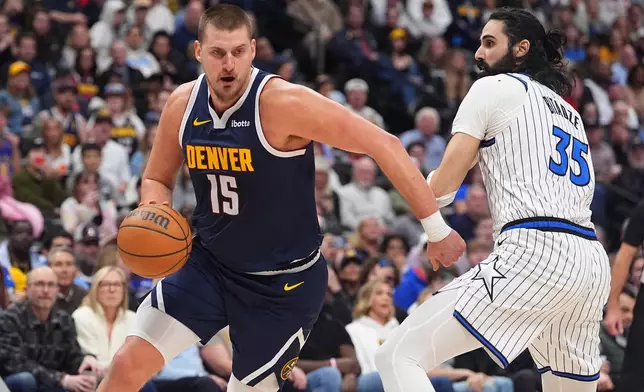 Denver Nuggets center Nikola Jokić drives (15) past Orlando Magic center Goga Bitadze (35) in the second half of an NBA basketball game Thursday, Dec. 18, 2025, in Denver. (AP Photo/David Zalubowski)