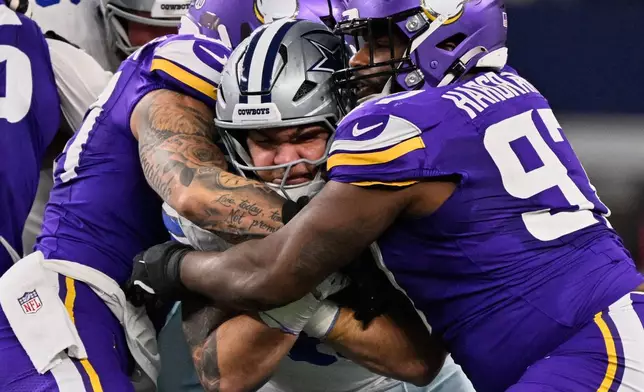 Dallas Cowboys running back Hunter Luepke, center, is stopped by Minnesota Vikings defensive tackle Javon Hargrave, right, and linebacker Blake Cashman during the first half of an NFL football game Sunday, Dec. 14, 2025, in Arlington, Texas. (AP Photo/Jerome Miron)