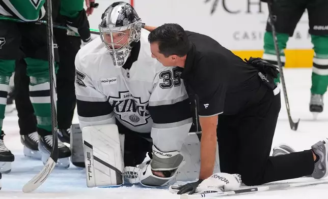 Los Angeles Kings goaltender Darcy Kuemper (35) is tended by a trainer after colliding on a play against Dallas Stars right wing Mikko Rantanen during the first period of an NHL hockey game Monday, Dec. 15, 2025, in Dallas. (AP Photo/Julio Cortez)