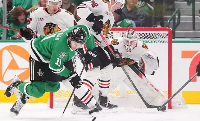 Dallas Stars right wing Nathan Bastian (11) reaches for the puck in front of Chicago Blackhawks defenseman Louis Crevier (46), defenseman Alex Vlasic (72) and goaltender Arvid Soderblom, right, during the second period of an NHL hockey game Saturday, Dec. 27, 2025, in Dallas. (AP Photo/LM Otero)
