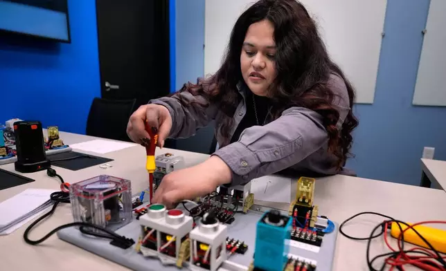 Maintenance technician Liz Cardenas completes a task on an electronics test platform at a training area in a Walmart distribution center Thursday, Sept. 25, 2025, in Bentonville, Ark. (AP Photo/Charlie Riedel)