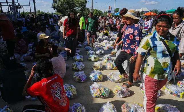 Evacuees wait to receive donation from local charity as they take refuge in Banteay Menchey provincial town, Cambodia, Saturday, Dec. 13, 2025, after fleeing homes following fighting between Thailand and Cambodia. (AP Photo/Heng Sinith)