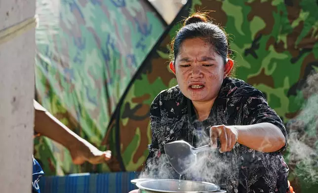 An evacuee cooks soup as she takes refuge in Banteay Menchey provincial town, Cambodia, Saturday, Dec. 13, 2025, after fleeing home following fighting between Thailand and Cambodia. (AP Photo/Heng Sinith)