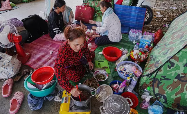 Evacuees cook food as they take refuge in Banteay Menchey provincial town, Cambodia, Saturday, Dec. 13, 2025, after fleeing homes following fighting between Thailand and Cambodia. (AP Photo/Heng Sinith)