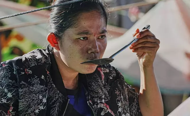 An evacuee tastes soup as she takes refuge in Banteay Menchey provincial town, Cambodia, Saturday, Dec. 13, 2025, after fleeing from home following fighting between Thailand and Cambodia. (AP Photo/Heng Sinith)