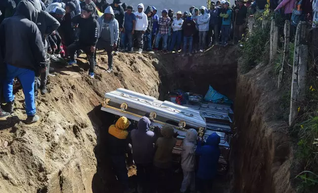 People bury victims in a mass grave following an attack by armed men on a military post and a police station in Nahuala, Guatemala, Sunday, Dec. 14, 2025. (AP Photo/Mariano Rosales)