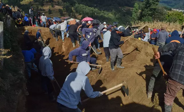 People bury victims in a mass grave following an attack by armed men on a military post and a police station in Nahuala, Guatemala, Sunday, Dec. 14, 2025. (AP Photo/Mariano Rosales)