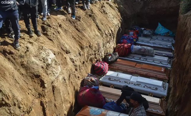 People bury victims in a mass grave following an attack by armed men on a military post and a police station in Nahuala, Guatemala, Sunday, Dec. 14, 2025. (AP Photo/Mariano Rosales)