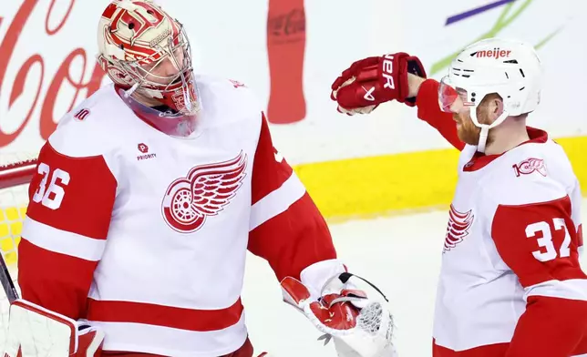Detroit Red Wings goalie John Gibson, left, is congratulated by J.T. Compher after defeating the Calgary Flames in NHL hockey action in Calgary, on Wednesday, Dec. 10, 2025. (Larry MacDougal/The Canadian Press via AP)