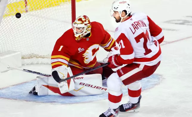 Detroit Red Wings' Dylan Larkin, right, scores on Calgary Flames goalie Devin Cooley during the second period of an NHL hockey game in Calgary, Alberta, on Wednesday, Dec. 10, 2025. (Larry MacDougal/The Canadian Press via AP)