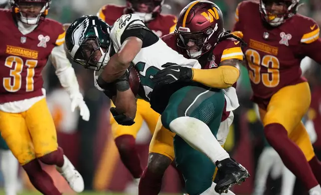 Philadelphia Eagles running back Saquon Barkley, center left, runs for a touchdown against Washington Commanders cornerback Noah Igbinoghene, center right, during the second half of an NFL football game, Saturday, Dec. 20, 2025, in Landover, Md. (AP Photo/Stephanie Scarbrough)