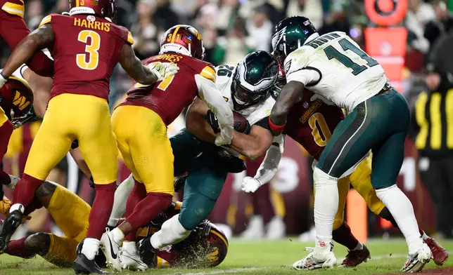 Philadelphia Eagles running back Saquon Barkley (26) scores a touchdown against Washington Commanders cornerback Jonathan Jones (31) during the second half of an NFL football game, Saturday, Dec. 20, 2025, in Landover, Md. (AP Photo/Nick Wass)