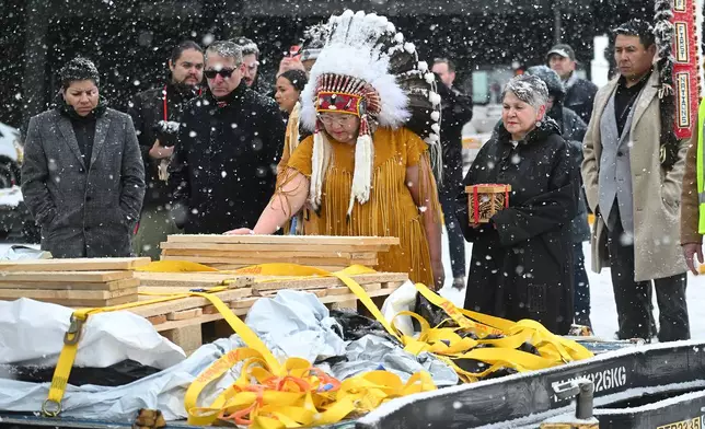Assembly of First Nations National Chief Cindy Woodhouse Nepinak places her hand on indigenous and cultural artifacts at Trudeau Airport in Montreal, Saturday, Dec. 6, 2025, after they were returned by the Vatican. (Graham Hughes /The Canadian Press via AP)