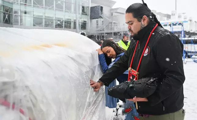 Katisha Paul of the Lil'wat and Tsartlip Nations, left, and Peyal Laceese of the Tsilhqot'in nation touch a crate containing indigenous artifacts and cultural items at Trudeau Airport in Montreal, Saturday, Dec. 6, 2025, after they were returned by the Vatican. (Graham Hughes /The Canadian Press via AP)