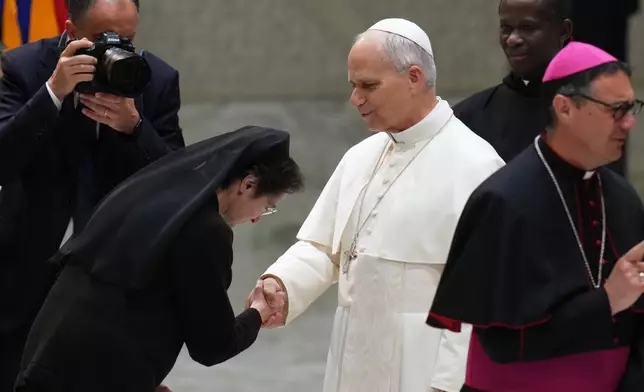 Pope Leo XIV, center, shakes hands with Sister Raffaella Petrini, President of the Vatican City State at the end of an audience with donors of the Christmas tree and nativity scene set up in St. Peter's Square, in the Paul VI Hall, at the Vatican, Monday, Dec. 15, 2025. (AP Photo/Alessandra Tarantino)