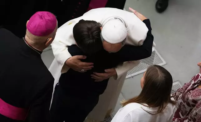 Pope Leo XIV hugs a child at the end of an audience with donors of the Christmas tree and nativity scene set up in St. Peter's Square, in the Paul VI Hall, at the Vatican, Monday, Dec. 15, 2025. (AP Photo/Alessandra Tarantino)