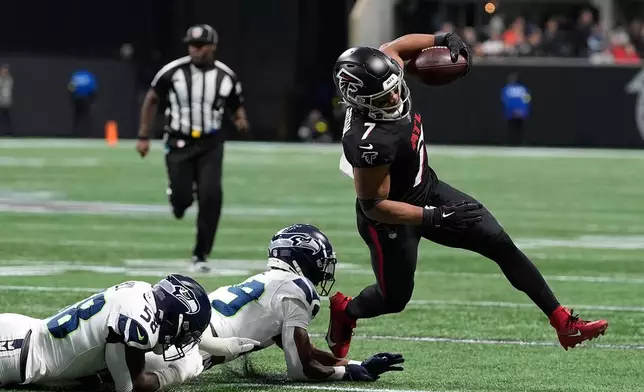 Atlanta Falcons running back Bijan Robinson (7) avoids tackles from Seattle Seahawks linebacker Derick Hall (58) and cornerback Josh Jobe (29) during the first half of an NFL football game, Sunday, Dec. 7, 2025, in Atlanta. (AP Photo/Brynn Anderson)