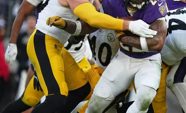 Baltimore Ravens running back Derrick Henry (22) is tackled by Pittsburgh Steelers linebacker T.J. Watt (90) during the second half of an NFL football game, Sunday, Dec. 7, 2025, in Baltimore. (AP Photo/Stephanie Scarbrough)