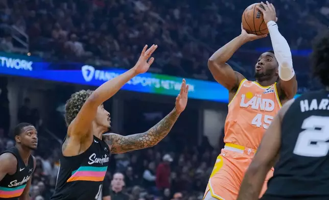 Cleveland Cavaliers guard Donovan Mitchell (45) shoots over San Antonio Spurs forward Jeremy Sochan, left, in the first half of an NBA basketball game Friday, Dec. 5, 2025, in Cleveland. (AP Photo/Sue Ogrocki)