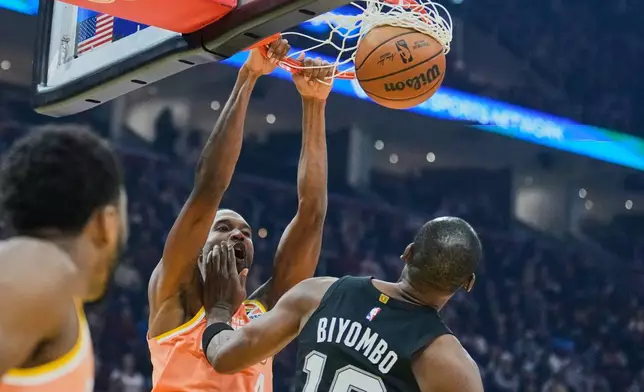 Cleveland Cavaliers center Evan Mobley (4) dunks over San Antonio Spurs center Bismack Biyombo (18) in the fist half of an NBA basketball game Friday, Dec. 5, 2025, in Cleveland. (AP Photo/Sue Ogrocki)