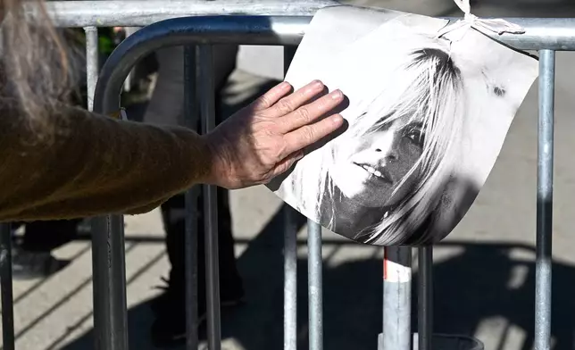 A woman touches a poster showing actor Brigitte Bardo near her home in Saint-Tropez, southern France, Sunday, Dec. 28, 2025 after the French 1960s sex symbol who became one of the greatest screen sirens of the 20th century and later a militant animal rights activist and far-right supporter, has died. She was 91. (AP Photo/Philippe Magoni)
