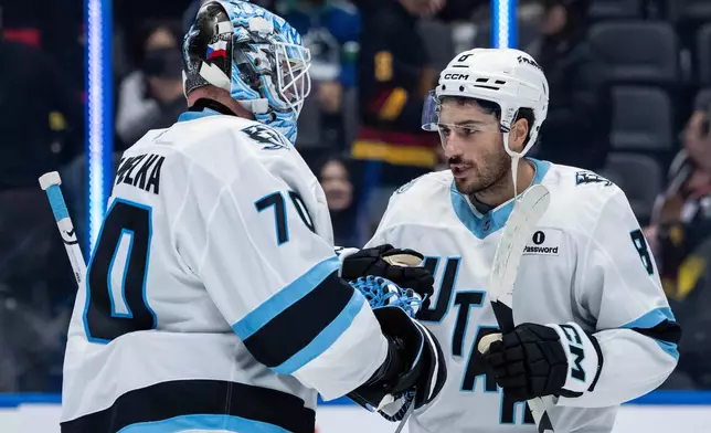 Utah Mammoth goaltender Karel Vejmelka (70) and Nick Schmaltz (8) celebrate after their team defeated the Vancouver Canucks in an NHL hockey game in Vancouver, British Columbia, Friday, Dec. 5, 2025. (Ethan Cairns/The Canadian Press via AP)