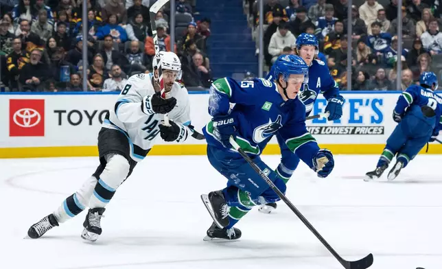 Utah Mammoth's Nick Schmaltz (8) pursues Vancouver Canucks' Elias Pettersson (25) who skates with the puck during the second period of an NHL hockey game in Vancouver, British Columbia, Friday, Dec. 5, 2025. (Ethan Cairns/The Canadian Press via AP)