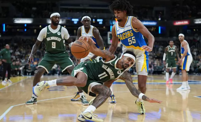 Milwaukee Bucks guard Gary Harris (11) slips in front of Indiana Pacers guard Ethan Thompson (55) during the second half of an NBA basketball game in Indianapolis, Tuesday, Dec. 23, 2025. (AP Photo/AJ Mast)