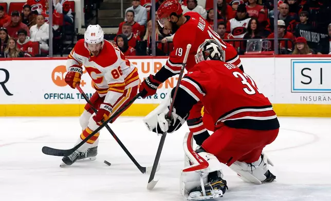 Carolina Hurricanes' K'Andre Miller (19) strips the puck from Calgary Flames' Joel Farabee (86) in front of Carolina Hurricanes goaltender Brandon Bussi, right, during the first period of an NHL hockey game in Raleigh, N.C., Sunday, Nov. 30, 2025. (AP Photo/Karl DeBlaker)