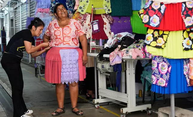 A dressmaker measures a customer at shop in Cochabamba, Bolivia, Monday, Sept. 15, 2025. (AP Photo/Juan Karita)