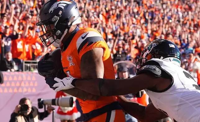 Denver Broncos wide receiver Courtland Sutton makes a catch to score a touchdown against Jacksonville Jaguars cornerback Jourdan Lewis during the first half of an NFL football game in Denver, Sunday, Dec. 21, 2025. (AP Photo/David Zalubowski)