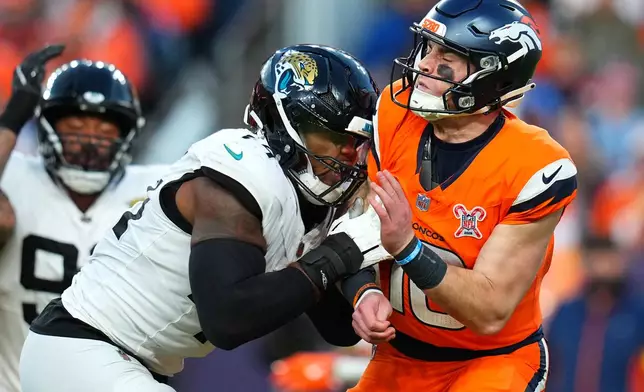 Jacksonville Jaguars defensive end Travon Walker, front left, tackles Denver Broncos quarterback Bo Nix, right, during the second half of an NFL football game in Denver, Sunday, Dec. 21, 2025. (AP Photo/Jack Dempsey)