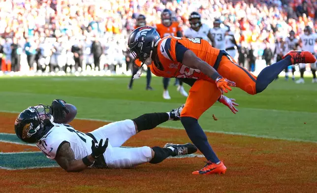 Jacksonville Jaguars wide receiver Parker Washington (11) scores a touchdown against Denver Broncos cornerback Ja'Quan McMillian, right, during the first half of an NFL football game in Denver, Sunday, Dec. 21, 2025. (AP Photo/Jack Dempsey)