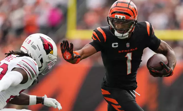 Cincinnati Bengals wide receiver Ja'Marr Chase (1) runs in a touchdown as Arizona Cardinals cornerback Denzel Burke defends during the first half of an NFL football game Sunday, Dec. 28, 2025, in Cincinnati. (AP Photo/Jeff Dean)