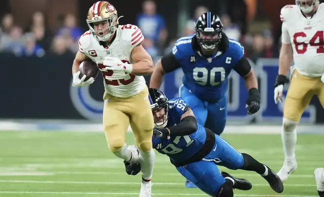 San Francisco 49ers running back Christian McCaffrey (23) runs past Indianapolis Colts defensive end Laiatu Latu (97) and defensive tackle Grover Stewart (90) during the first half of an NFL football game, Monday, Dec. 22, 2025, in Indianapolis. (AP Photo/AJ Mast)