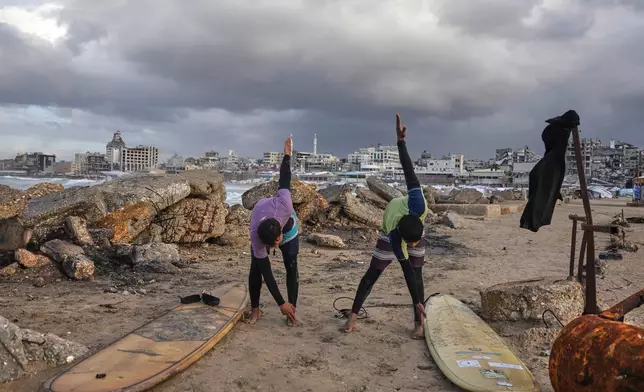 Palestinian Khalil Abu Jayyab, right, and Tahseen Abu Assi warm up before surfing on the beach in Gaza City, Sunday, Dec. 28, 2025. (AP Photo/Jehad Alshrafi)