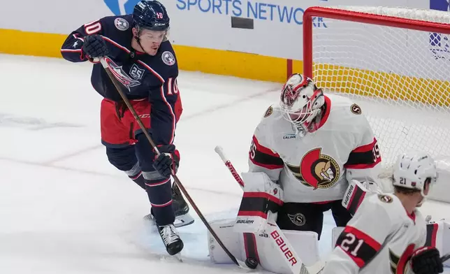 Columbus Blue Jackets left wing Dmitri Voronkov (10) reaches for the puck next to Ottawa Senators goaltender Linus Ullmark (35) in the first period of an NHL hockey game Thursday, Dec. 11, 2025, in Columbus, Ohio. (AP Photo/Sue Ogrocki)
