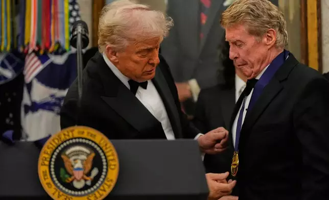 President Donald Trump, left, presents Michael Crawford with his Kennedy Center Honors medal in the Oval Office of the White House, Saturday, Dec. 6, 2025, in Washington. (AP Photo/Julia Demaree Nikhinson)