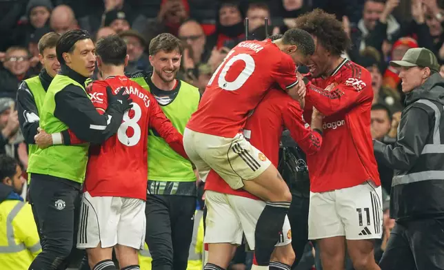 Manchester United players celebrate after Manchester United's Diogo Dalot scored his side's opening goal during the English Premier League soccer match between Manchester United and West Ham United in Manchester, England, Thursday, Dec. 4, 2025. (AP Photo/Ian Hodgson)