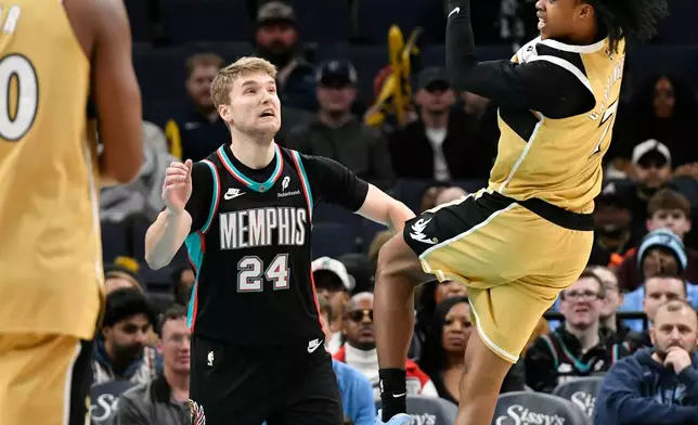 Washington Wizards guard Bub Carrington, right, passes the ball over Memphis Grizzlies guard Cam Spencer (24) in the first half of an NBA basketball game Saturday, Dec. 20, 2025, in Memphis, Tenn. (AP Photo/Brandon Dill)
