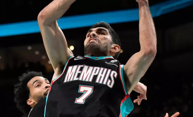 Memphis Grizzlies forward/center Santi Aldama grabs a rebound ahead of Washington Wizards forward Justin Champagnie in the first half of an NBA basketball game, Saturday, Dec. 20, 2025, in Memphis, Tenn. (AP Photo/Brandon Dill)