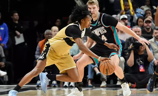 Washington Wizards guard Bub Carrington drives against Memphis Grizzlies guard Cam Spencer (24) in the first half of an NBA basketball game, Saturday, Dec. 20, 2025, in Memphis, Tenn. (AP Photo/Brandon Dill)