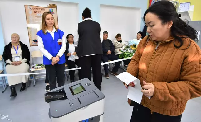 A voter holds a ballot during the parliamentary elections at a polling station in Tash-Dobo, south of Bishkek, Kyrgyzstan, Sunday, Nov. 30, 2025. (AP Photo/Vladimir Voronin)