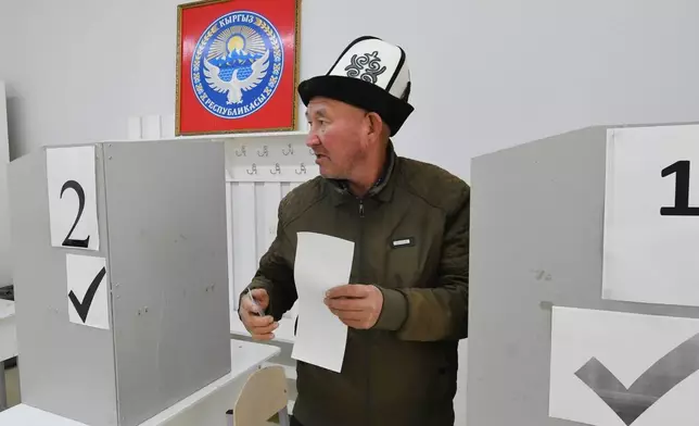 A voter holds his ballot during the parliamentary elections at a polling station in Tash-Dobo, south of Bishkek, Kyrgyzstan, Sunday, Nov. 30, 2025. (AP Photo/Vladimir Voronin)