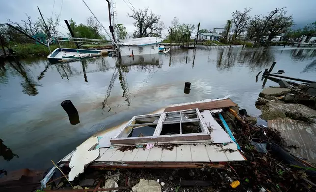 FILE - An oil sheen drifts between a sunken shrimp boat and pieces of a destroyed home along Bayou Pointe au Chien in the aftermath of Hurricane Ida in Pointe-aux-Chenes, La., Tuesday, Sept. 14, 2021. (AP Photo/Gerald Herbert, File)