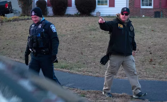 A FBI explosive ordnance agent talks with a Prince William County Police officers as agents investigate a house where the FBI made an arrest in Woodbridge, Va., Thursday, Dec. 4, 2025. (AP Photo/Cliff Owen)