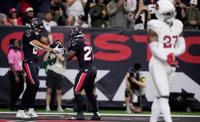 Houston Texans wide receiver Jayden Higgins, left, celebrates a Texans touchdown with Texans running back Woody Marks as Arizona Cardinals linebacker Akeem Davis-Gaither (27) pauses in the endzone during the first half of an NFL football game Sunday, Dec. 14, 2025, in Houston. (AP Photo/Ashley Landis)