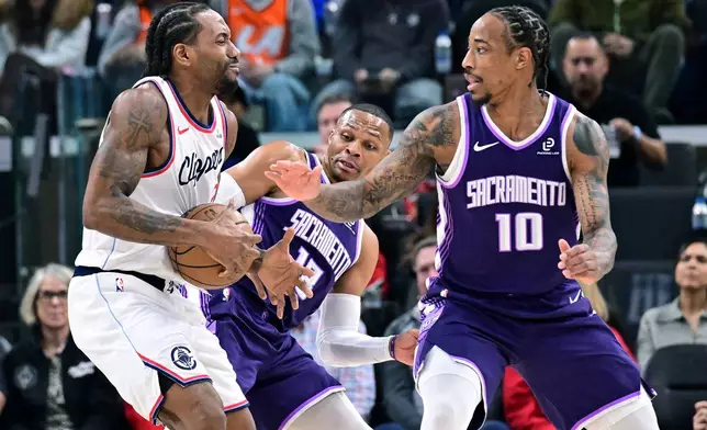 Sacramento Kings guard Russell Westbrook, center, and forward Demar Derozan (10) try to steal the ball from Los Angeles Clippers forward Kawhi Leonard, left, in the first half of an NBA basketball game Tuesday, Dec. 30, 2025, in Inglewood, Calif. (AP Photo/Wally Skalij)