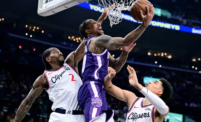Sacramento Kings guard/forward Demar Derozan, front, is fouled by Los Angeles Clippers forward Kawhi Leonard (2) as teammate Yanic Konan Niederhäuser tries to help on defense in the first half of an NBA basketball game Tuesday, Dec. 30, 2025, in Inglewood, Calif. (AP Photo/Wally Skalij)